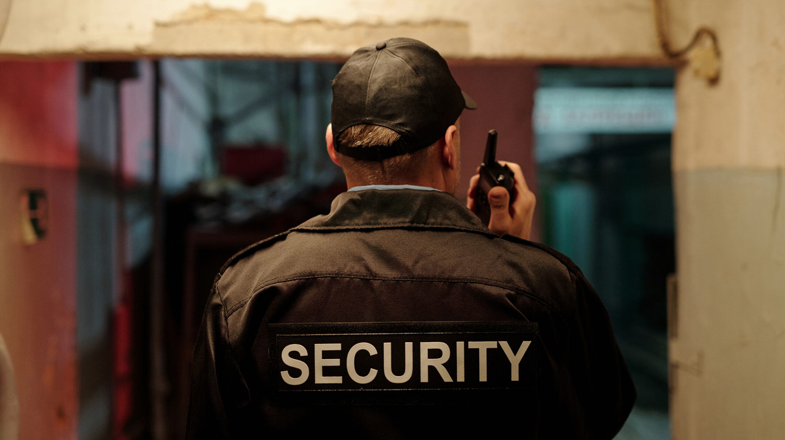 A vigilant security guard close-up with a walkie-talkie at a new gate, symbolizing enhanced safety and access control services
